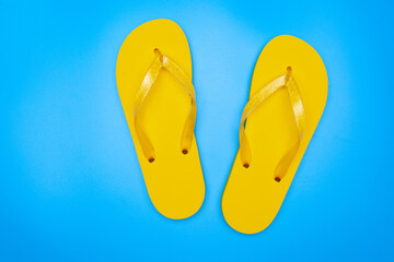 yellow rubber flip-flops isolated over blue background, pair of thongs, shot above