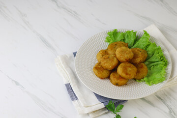 Perkedel Kentang or Potato cutlet, one of Indonesian food made from mashed potato, celery, spice, and fried. White marble background, copy space for text