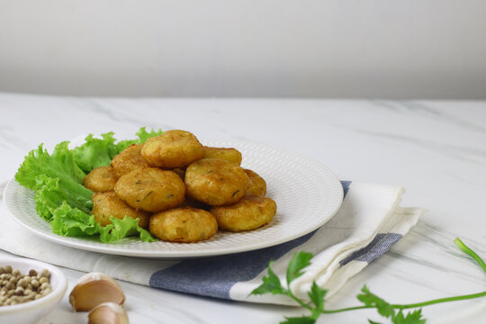 Perkedel Kentang or Potato cutlet, one of Indonesian food made from mashed potato, celery, spice, and fried. White marble background, copy space for text