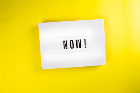 Lightbox with message NOW isolated on yellow background. Concept of motivation, hurry up sale announcement, start, beginning, buy now, register, join immediately, in stock, new trends, presently - Powered by Adobe