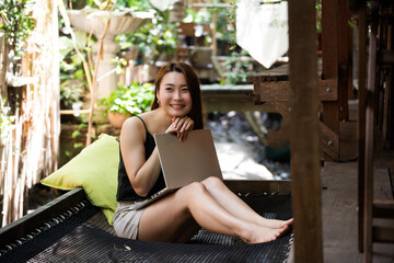 Happy freelance woman is relaxing on comfortable couch and using laptop at home.communicates on Internet with customer.