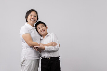 Portrait of Grandmother and grandchild hugging, looking at camera and smiling, on gray background
