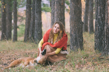 Young woman walking with her dog in autumn mountain forest