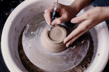 Female potter hands working with clay in workshop. White desk on background