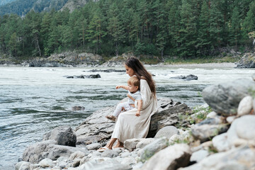 Young mother wearing white dress walking and enjoying  with little kid boy near mountain river outdoor