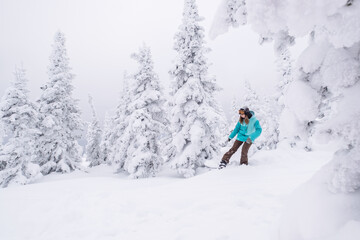 Snowboarder female riding on winter snow cowered slop on snowboard. Powder Day, winter holiday in...