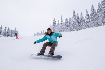 Snowboarder female riding on winter snow cowered slop on snowboard. Powder Day, winter holiday in...