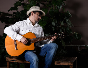 Obraz premium Músico cubano con sombrero en una plaza en la noche ejecutando una guitarra española