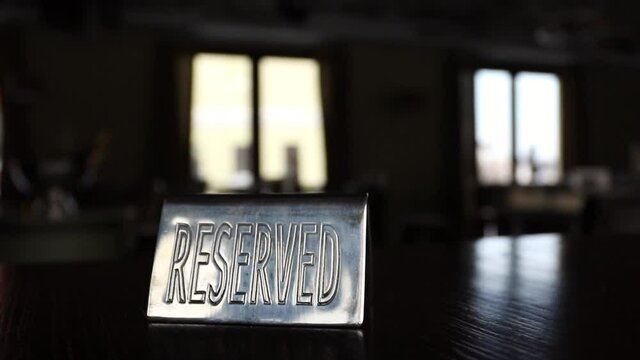 A plate reserved on a dark table in a cafe opposite the windows. High quality FullHD footage