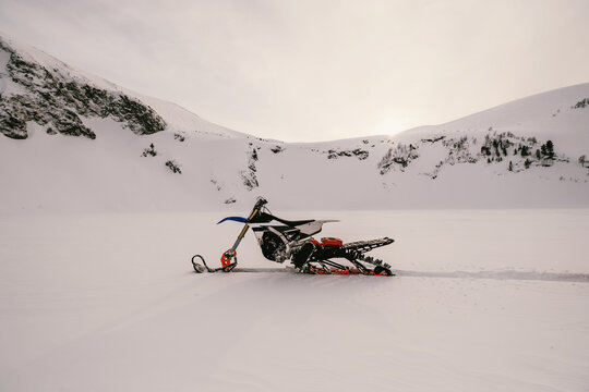 Snowbike standing on frozen lake with snow powder between snowy mountains