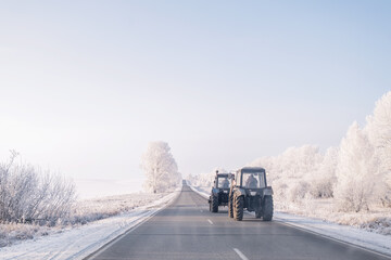 Tractor on the winter road, sunny day, snow cowered trees