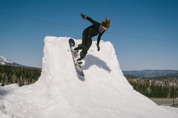 Snowboarder female jumping on quarter pipe snowboard in winter sunny day. Freestyle snowboard...