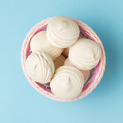 Top view of a basket of meringue on a blue background.