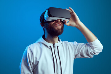 Bearded man enjoying virtual reality glasses against blue background