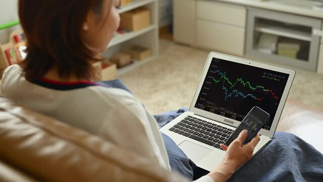 スマートフォンで株式取引をする妊婦の女性
