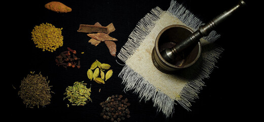 Closeup Composition of Mortar and pestle with Various Indian Herbs and spices in a isolated dark background with copy space for inscription. Masala. Ingredients. Cuisine. Seasoning. 