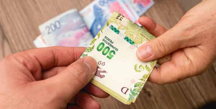 Dinheiro da Argentina. Neg&oacute;cio entre duas pessoas com c&eacute;dulas do peso argentino - ARS. Economia argentina e neg&oacute;cios.