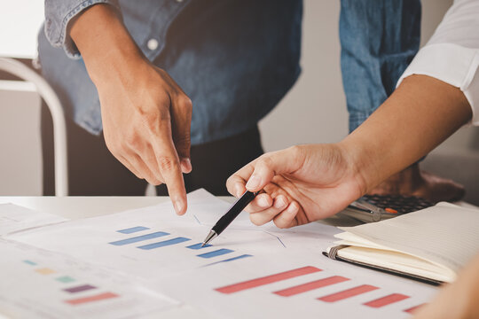 Discussion, Brainstorm asian young businessman, businesswoman are analyzing charts, graph on document, discussing economic strategy on paperwork for companies to growth on table at office, workplace.