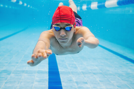 portrait of paralympic Swimmer young latin man Underwater Training In Pool with hand hypoplasia in disability concept