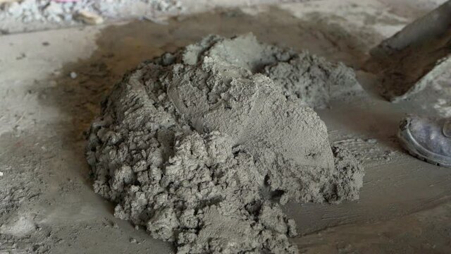 Worker mixes mortar with shovel. Handheld
