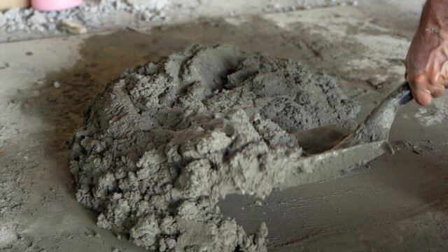 Worker mixes mortar with shovel. Slow-motion