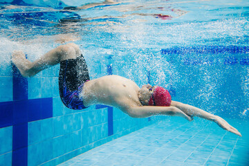 Paralympic Swimmer young latin man Underwater Training In Pool, disability concept