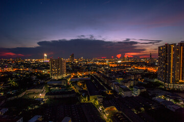Panorama background of city views, with colorful twilight sky, high-rise buildings (condominiums, offices, expressways) and blurred lights from roads and traffic.
