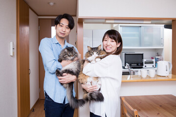 自宅でペットの猫を抱く日本人の若いカップル