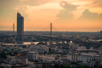 Panorama background of city views, with colorful twilight sky, high-rise buildings (condominiums, offices, expressways) and blurred lights from roads and traffic.
