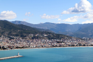 white lighthouse on the pier in Alanya port in Turkey surrounded by azure water of mediterranean sea