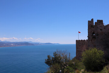 Naklejka premium turkish flag on the wall of the medieval Alanya fortress with azure sea on the background