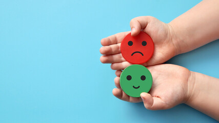 Mugs with an evil and kind face in the hands of a child. Negative and positive emotions of the child