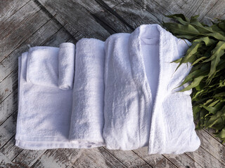 Terry bathrobe and towel on a wooden background. Spa, sauna, Russian bath.