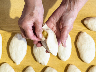 Fototapeta na wymiar female hand pinches a raw potato pie over pies