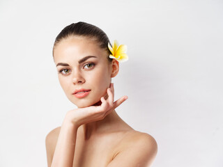 Fototapeta na wymiar pretty woman with bare shoulders makeup yellow flower hair close-up