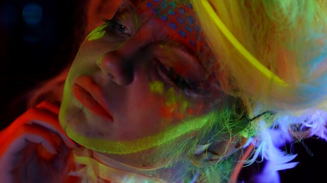 A woman with a neon body art in colored light in ultraviolet