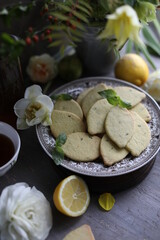 Lemon biscuits with basil on a table with floral decoration. Cookies and spring decor. Crunchy dessert.