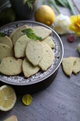 Lemon biscuits with basil on a table with floral decoration. Cookies and spring decor. Crunchy dessert.