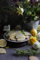Lemon biscuits with basil on a table with floral decoration. Cookies and spring decor. Crunchy dessert.