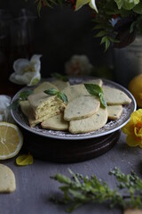 Lemon biscuits with basil on a table with floral decoration. Cookies and spring decor. Crunchy dessert.