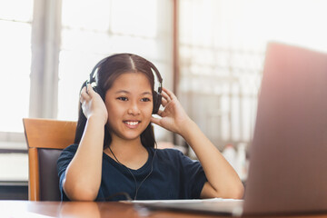 Asian young girl with headphone student using laptop study at home.