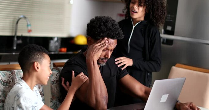 Stressed African father working at home children wanting attention