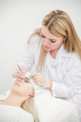 Professional cosmetologist  lengthening female lashes in beauty salon