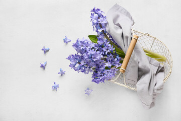Basket with beautiful hyacinth flowers on light background
