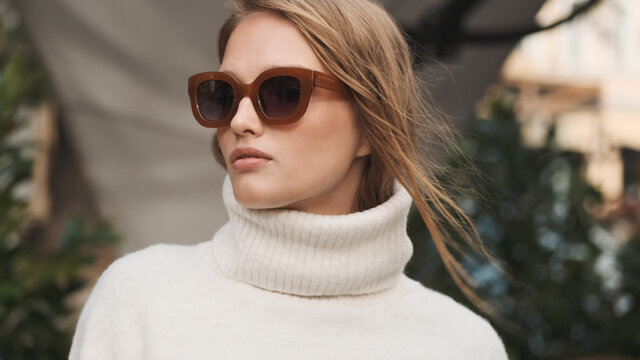 Gorgeous blond girl in sunglasses dressed in white cozy sweater
