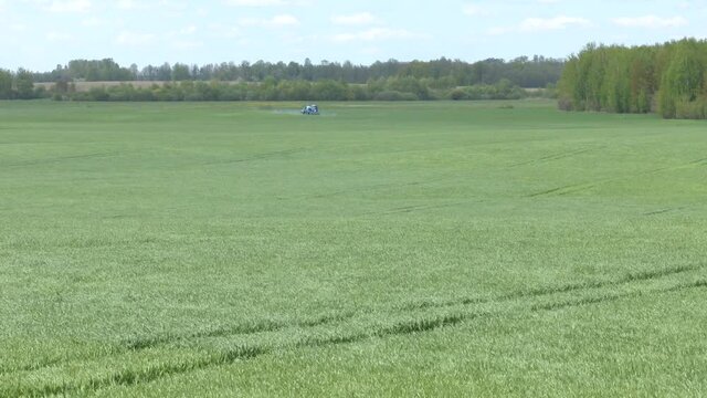 A farmer spraying on the spring wheat field with a John Deere tractor and a mamut topline sprayer. A farmer spraying on the spring wheat field with  tractor and a mamut topline sprayer.
