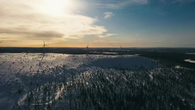 Aerial view of wind turbines on a snowy fell, windy evening in Lapland - tracking, drone shot