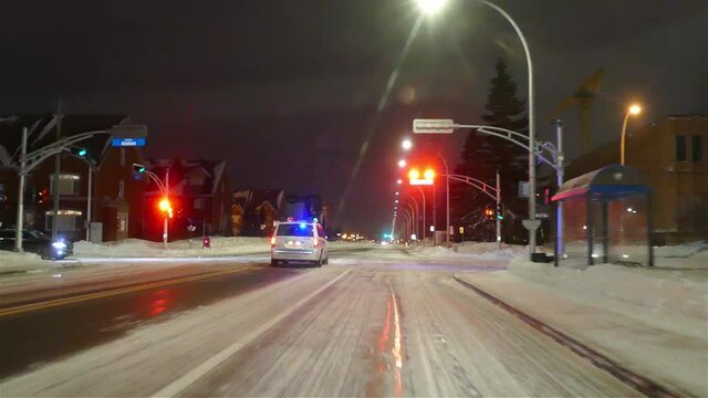 Police Car Running A Red Light With Emergency Lights On, Wintertime With Snow On Ground