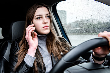 Fototapeta na wymiar Female driving car and talking on cellphone on bad weather condition.