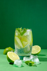 Refreshing summer cocktail mojito, fresh mint, lime and ice with hard light on green background....